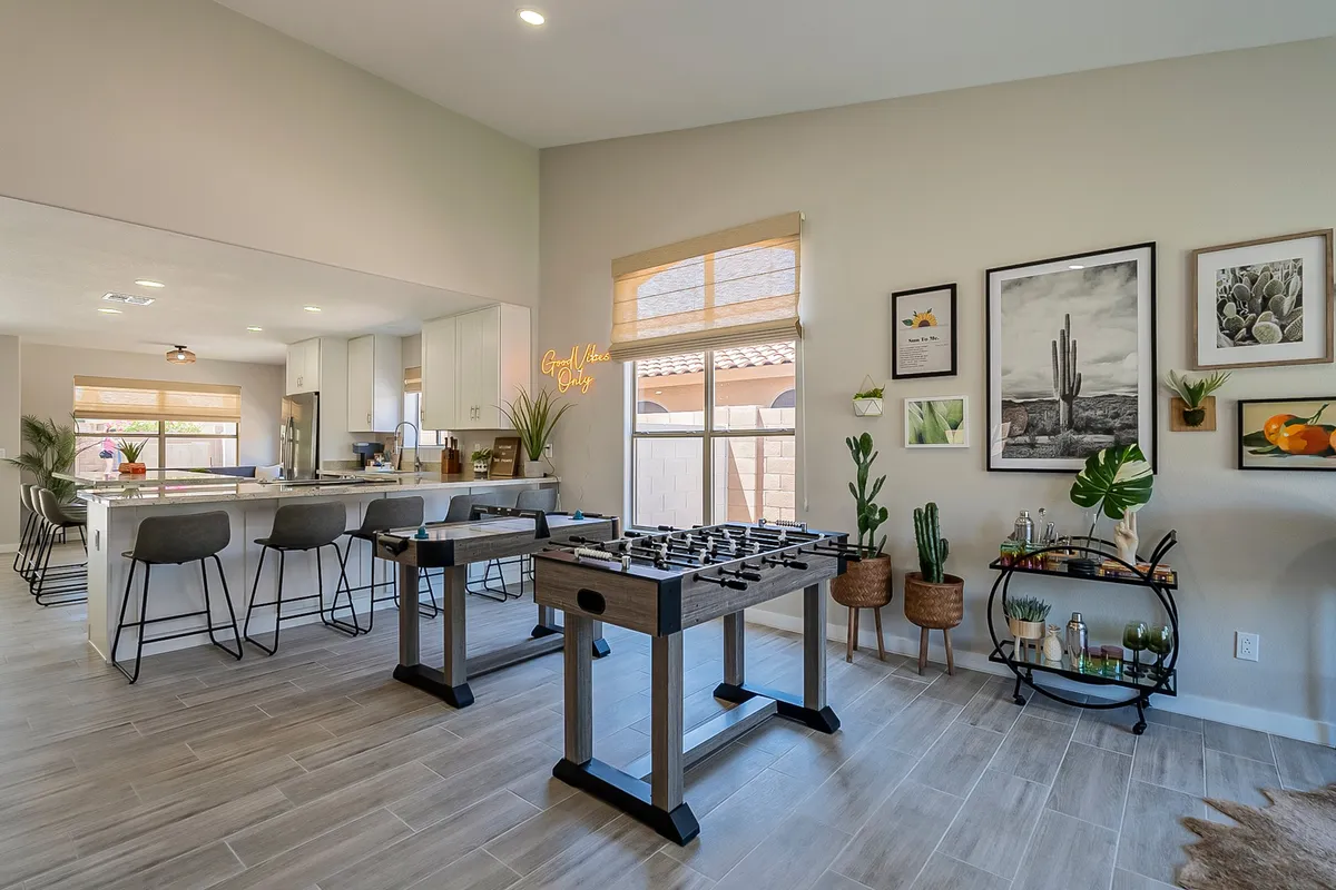 This bright, cheerful room combines a foosball table with a kitchen island, plants, and wall art. The setting suggests a joyful, open space that bridges game time with family dining and laid-back lounging—suitable for group games or quiet downtime as described in the section.