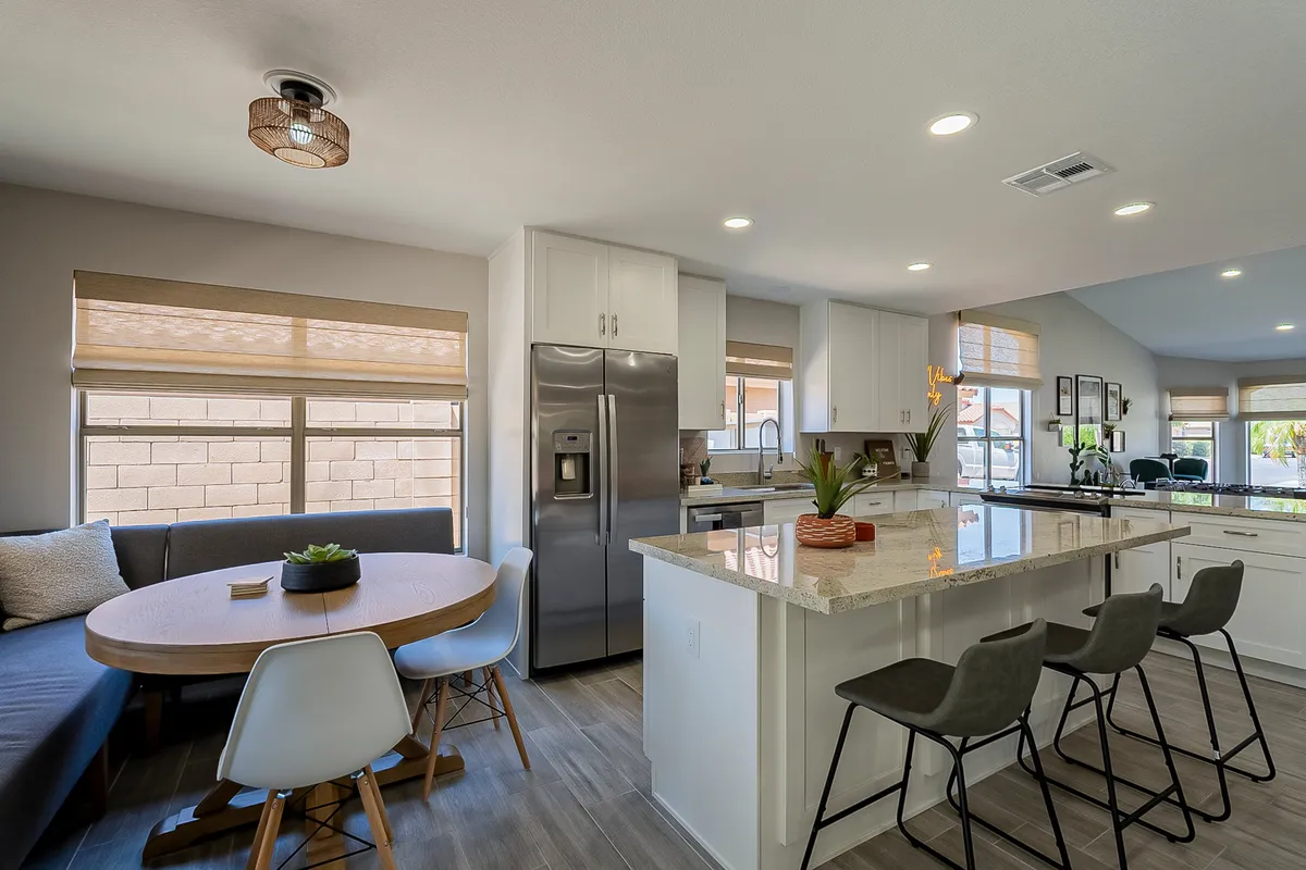 The image captures an inviting kitchen with a central island, a dining table set for meals, and a comfortable sofa seating area in the background. The open-plan design highlights the seamless connection between culinary and dining spaces, perfect for entertaining and family gatherings.